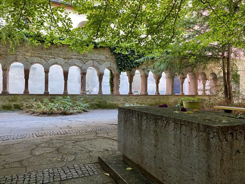 Der Grabstein von Walther von der Vogelweide mit dem Nordflügel des Kreuzgangs im Hintergrund